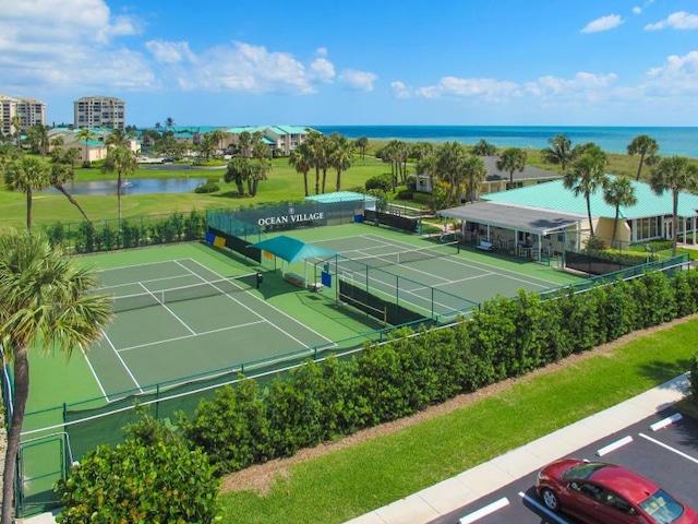 view of tennis court featuring fence and a water view