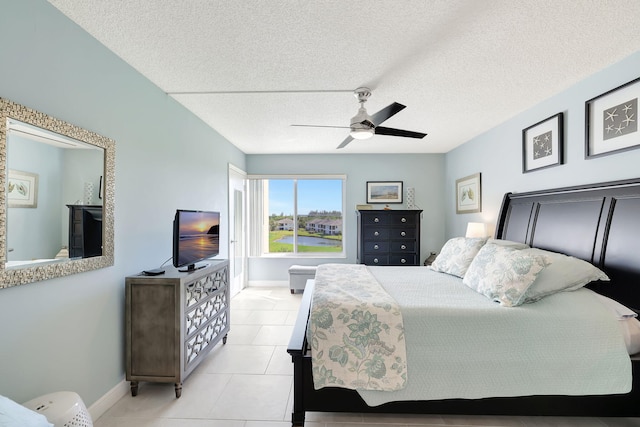 bedroom featuring ceiling fan, light tile patterned floors, baseboards, and a textured ceiling