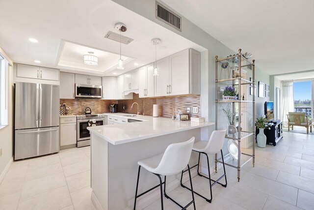 kitchen featuring white cabinets, decorative backsplash, stainless steel appliances, and kitchen peninsula