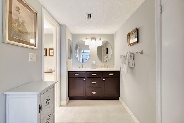 bathroom with tile patterned floors, vanity, and a textured ceiling