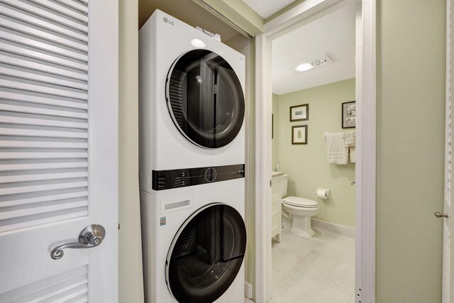 washroom with light tile patterned floors and stacked washer / drying machine