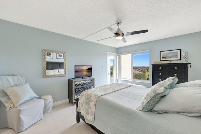 bedroom featuring light tile patterned floors, a ceiling fan, baseboards, and a textured ceiling