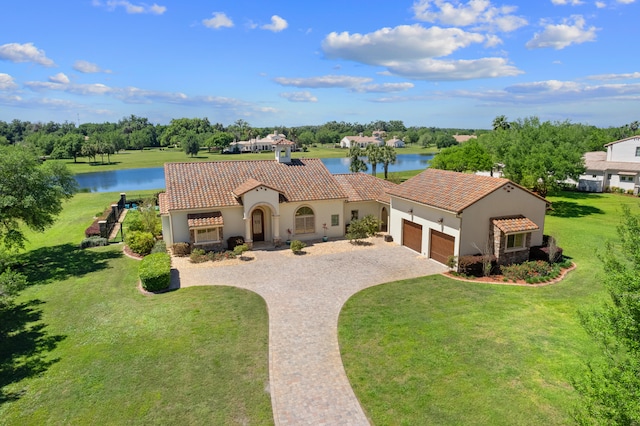 mediterranean / spanish home with a garage, a water view, and a front lawn