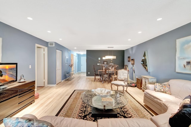 living room with light hardwood / wood-style flooring and a notable chandelier