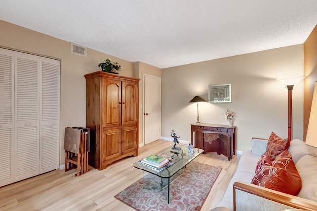 23 Westgate Ln Unit E, Boynton Beach, FL 33436 - living room featuring light wood-style flooring, a textured ceiling, baseboards, and visible vents