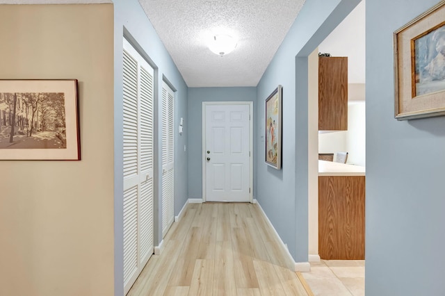 entryway with a textured ceiling and light wood-type flooring