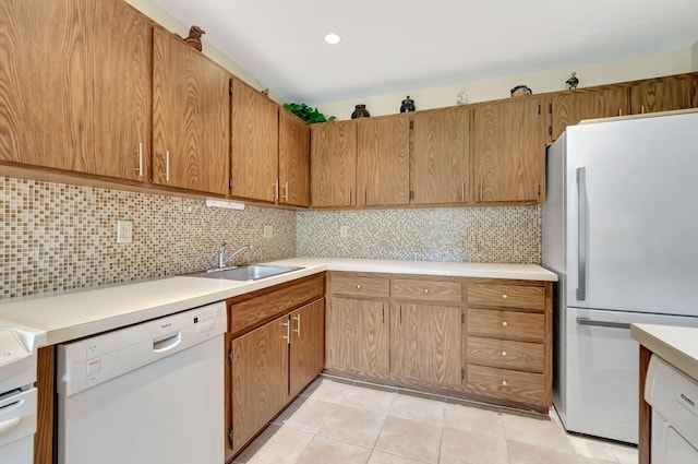 23 Westgate Ln Unit E, Boynton Beach, FL 33436 - kitchen with white appliances, light tile patterned flooring, light countertops, a sink, and backsplash