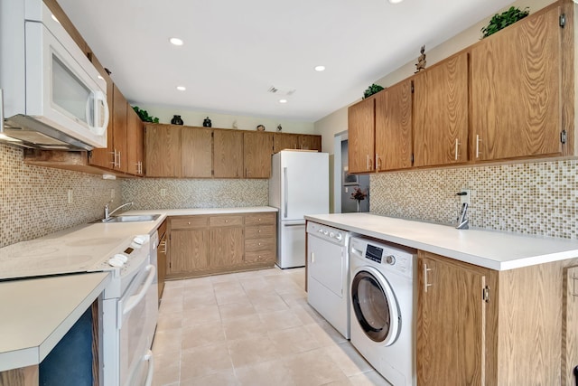 kitchen with white appliances, decorative backsplash, sink, and separate washer and dryer