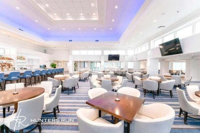 carpeted dining space featuring a raised ceiling, ornamental molding, and a towering ceiling