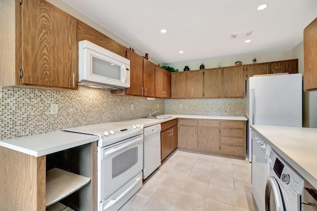 kitchen with light tile patterned floors, white appliances, sink, washer / dryer, and tasteful backsplash