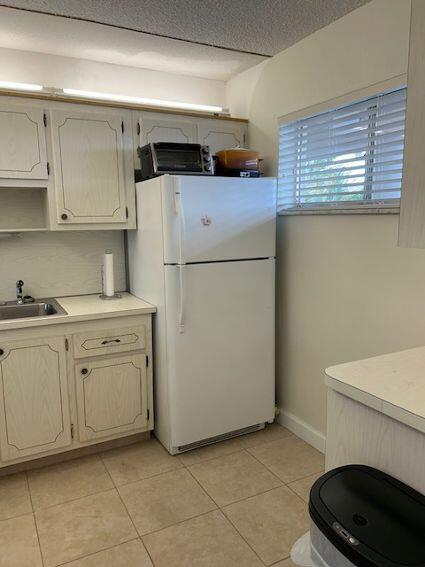 kitchen with sink, white refrigerator, a textured ceiling, and light tile floors