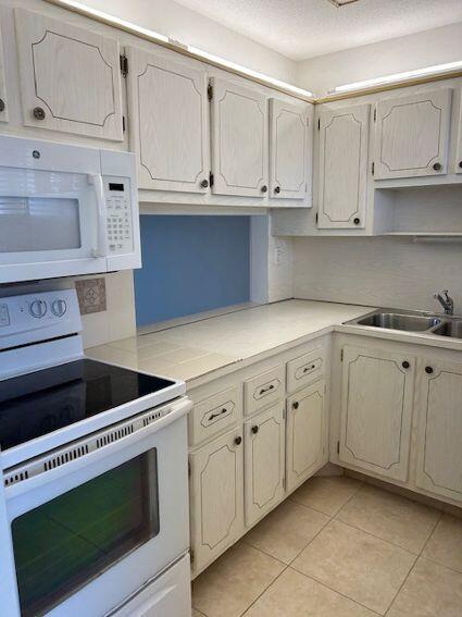 kitchen with white appliances, sink, and light tile floors