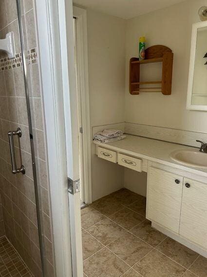 bathroom with walk in shower, tile floors, and vanity