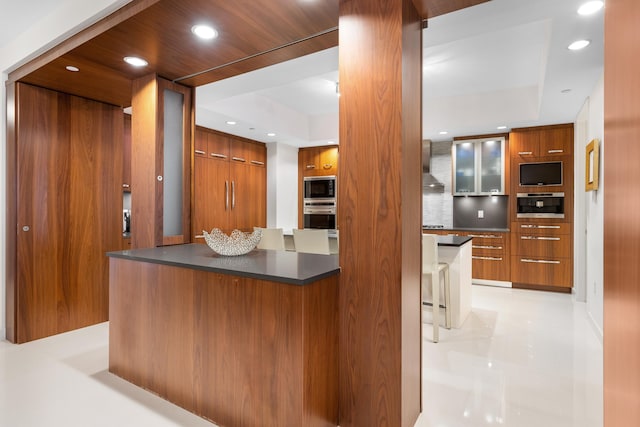 kitchen with backsplash, a kitchen island, stainless steel appliances, and wall chimney range hood