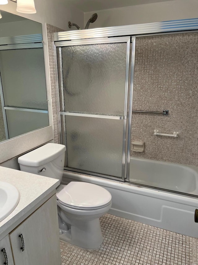 full bathroom with vanity, bath / shower combo with glass door, toilet, and tile flooring