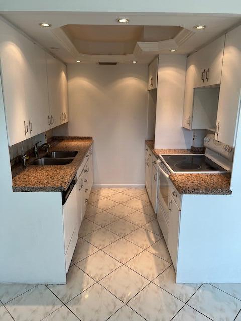 kitchen featuring white cabinets, a tray ceiling, and light tile floors