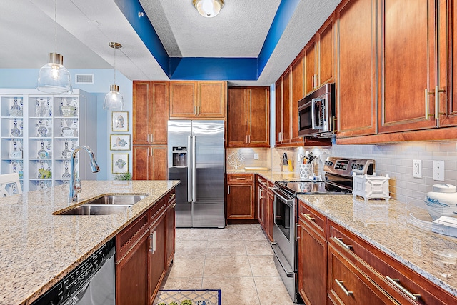 kitchen featuring decorative light fixtures, sink, backsplash, stainless steel appliances, and light stone countertops