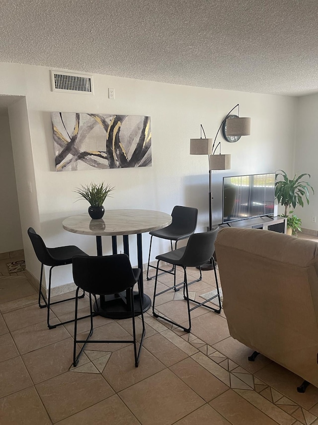 tiled dining area featuring a textured ceiling