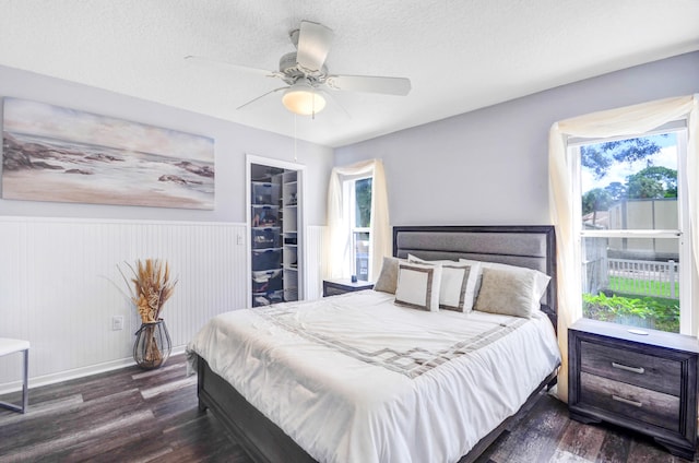 bedroom with a closet, dark wood-type flooring, a spacious closet, ceiling fan, and a textured ceiling