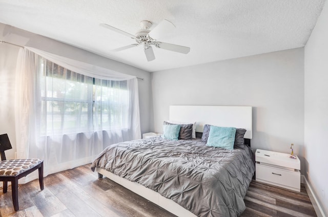 bedroom with dark hardwood / wood-style flooring, ceiling fan, and a textured ceiling