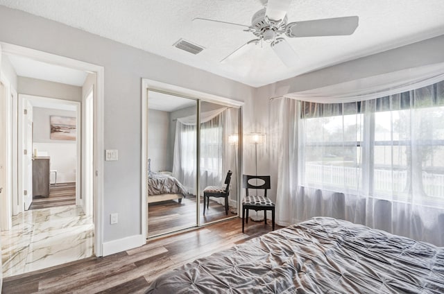 bedroom featuring a closet, ceiling fan, dark hardwood / wood-style flooring, and a textured ceiling