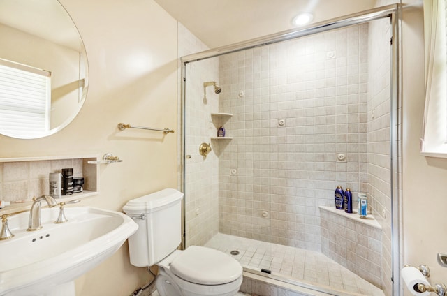 bathroom featuring sink, a shower with shower door, and toilet