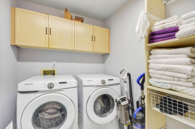 clothes washing area featuring hookup for a washing machine, cabinets, and washer and dryer