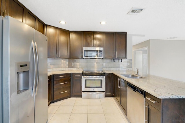 kitchen with sink, stainless steel appliances, kitchen peninsula, decorative backsplash, and light tile patterned flooring