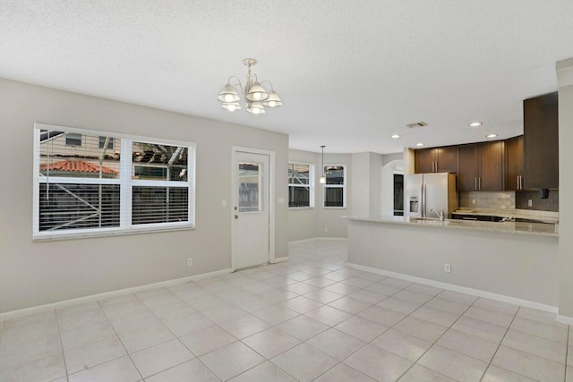 kitchen with a notable chandelier, stainless steel fridge, decorative light fixtures, dark brown cabinets, and light tile patterned floors