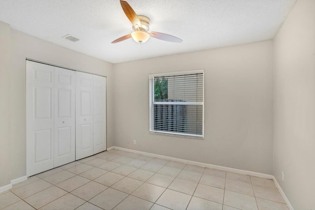 unfurnished bedroom featuring ceiling fan, light tile patterned floors, a textured ceiling, and a closet