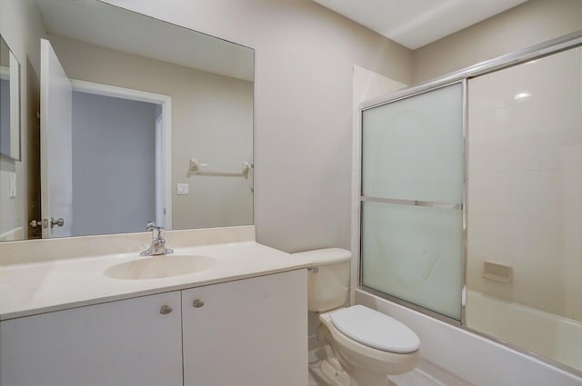 full bathroom with combined bath / shower with glass door, vanity, and toilet