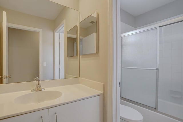 full bathroom featuring combined bath / shower with glass door, toilet, and vanity