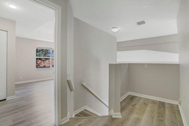 laundry room with light wood-type flooring and a textured ceiling