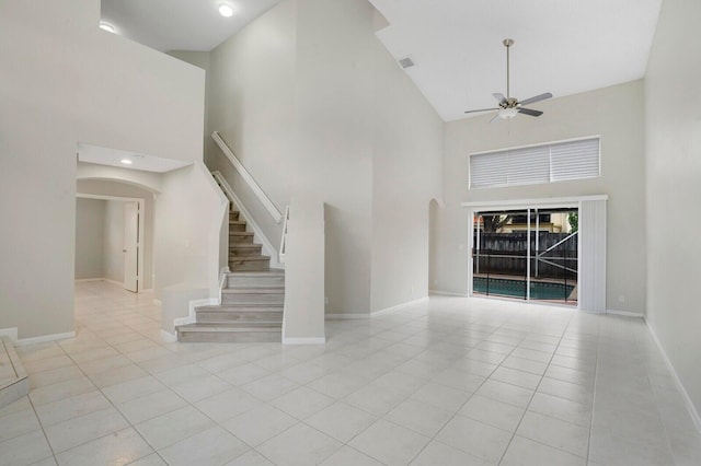 unfurnished living room with ceiling fan, a towering ceiling, and light tile patterned floors