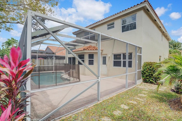 back of property with a fenced in pool and glass enclosure