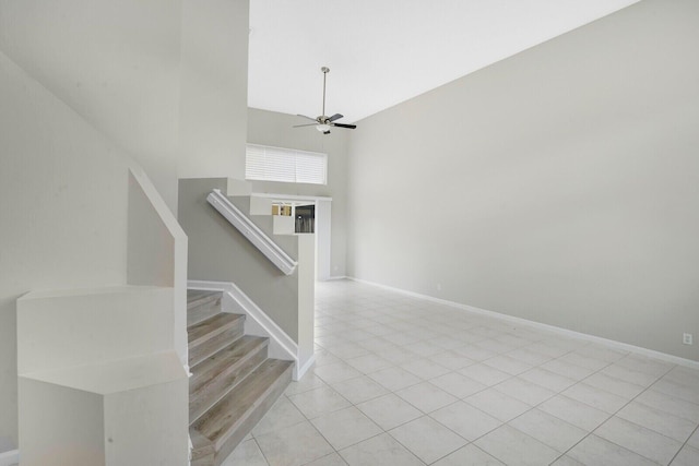 stairs featuring tile patterned flooring, ceiling fan, and a high ceiling