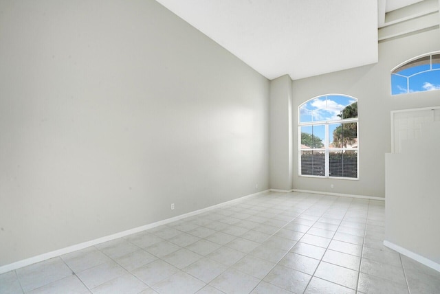 unfurnished room with light tile patterned floors and high vaulted ceiling