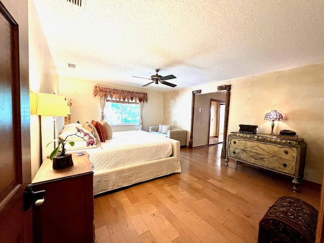 bedroom with light hardwood / wood-style flooring, ceiling fan, and a textured ceiling