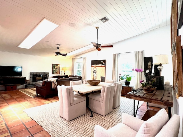 dining room with lofted ceiling with skylight, plenty of natural light, light tile flooring, and ceiling fan