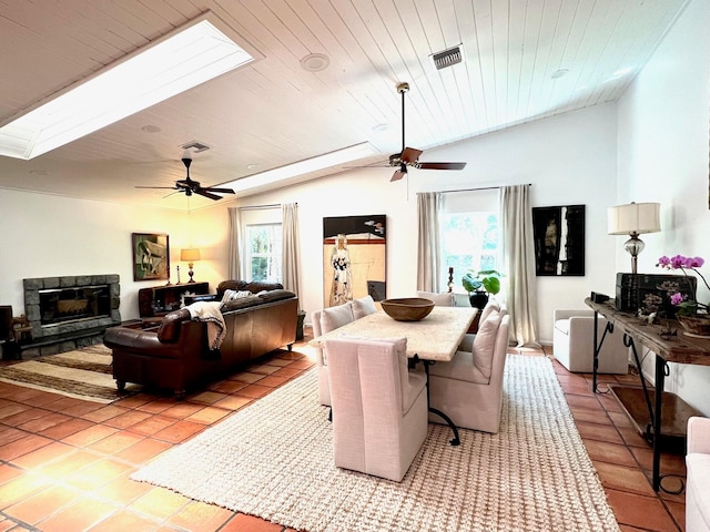 dining room with vaulted ceiling with skylight, wooden ceiling, ceiling fan, and light tile flooring