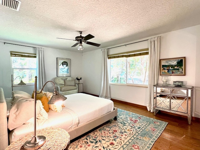 bedroom featuring ceiling fan, dark hardwood / wood-style floors, and a textured ceiling