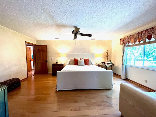 bedroom featuring light hardwood / wood-style flooring, ceiling fan, and a textured ceiling