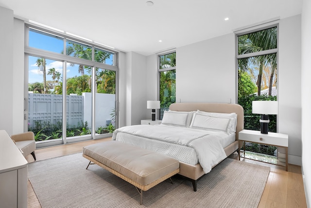 bedroom featuring light hardwood / wood-style flooring, expansive windows, and access to exterior