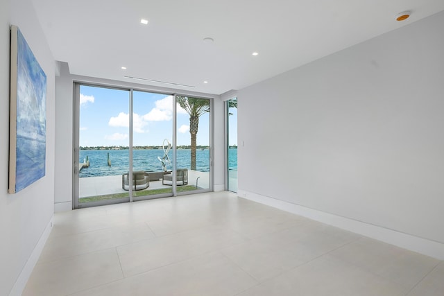 tiled spare room featuring a healthy amount of sunlight, expansive windows, and a water view