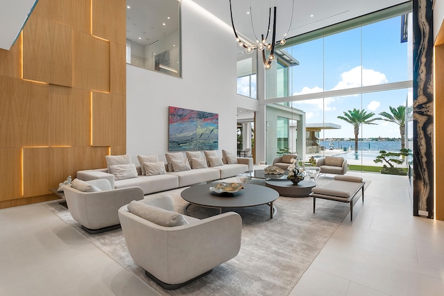 living room featuring a chandelier, a towering ceiling, light tile floors, and a water view