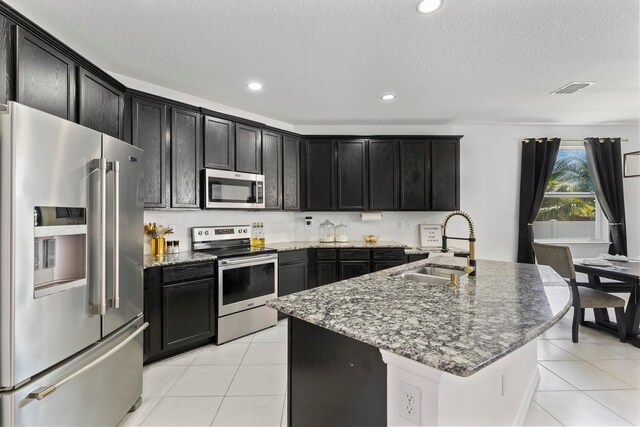 kitchen with appliances with stainless steel finishes, dark stone counters, and light tile patterned floors