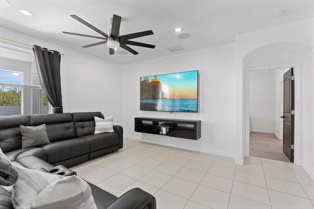 tiled living room featuring ceiling fan and a textured ceiling