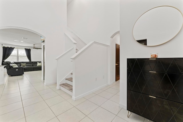 stairway with tile patterned flooring and a towering ceiling