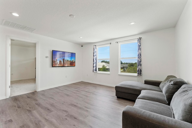 living room with a textured ceiling and light hardwood / wood-style floors