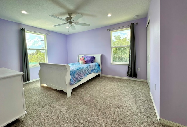 bedroom featuring ceiling fan, light carpet, and a textured ceiling